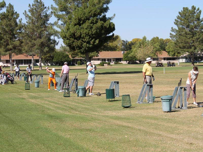 Golfers practicing on the grass driving range at Union Hills Golf Club in Sun City, AZ